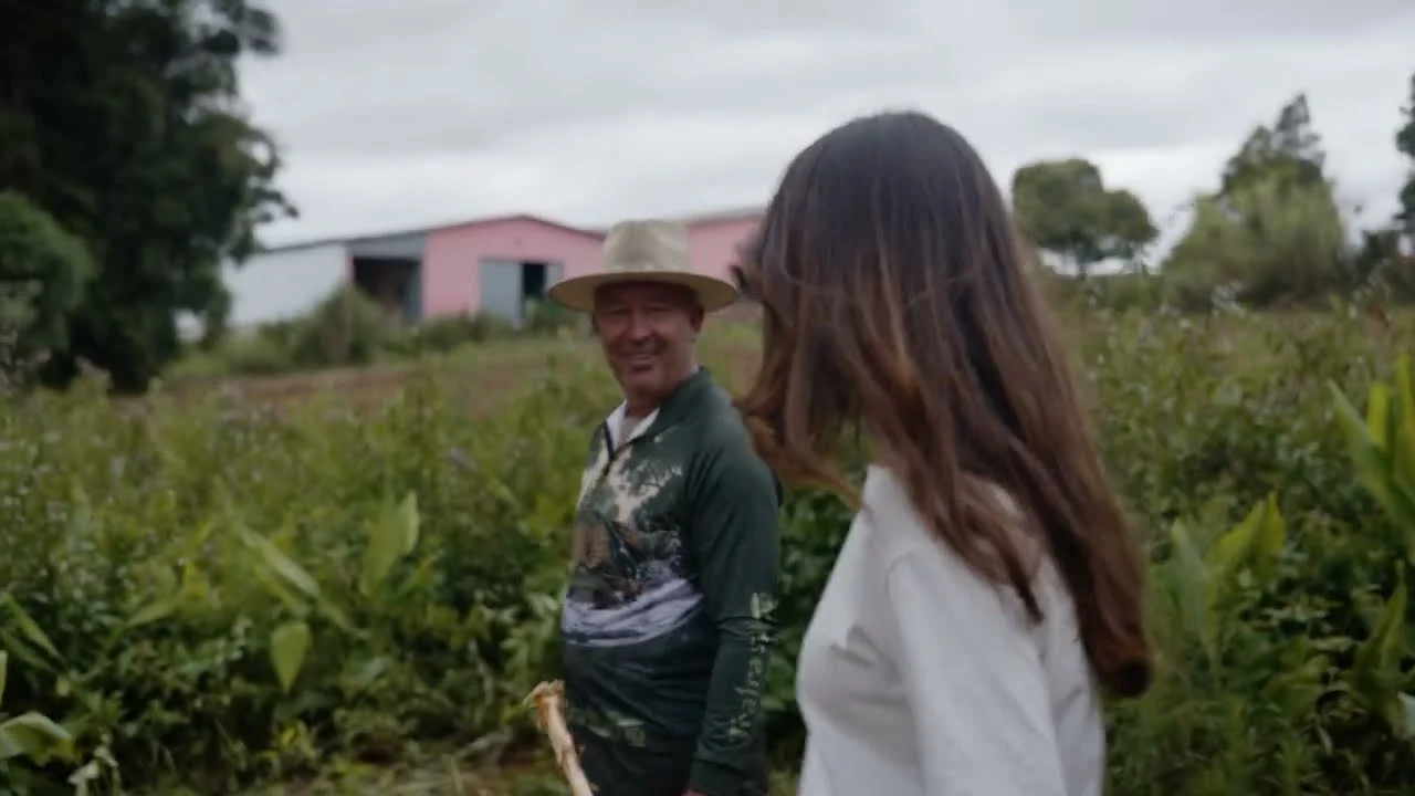 Elza walking with a farmer through the ora pro nobis field in Paraná, Brazil